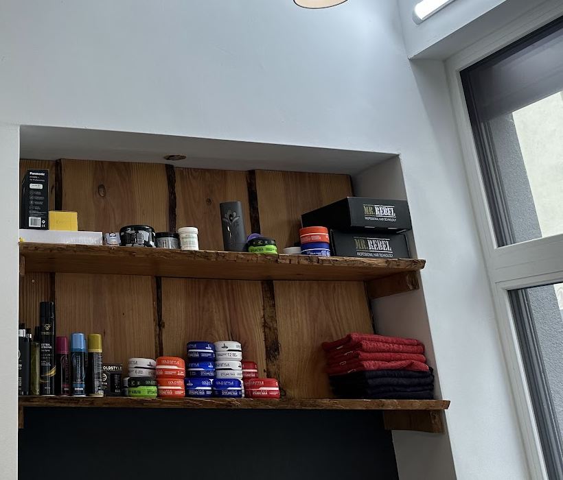 Holzregal mit Haarwachs, Stylingprodukten und roten Handtüchern