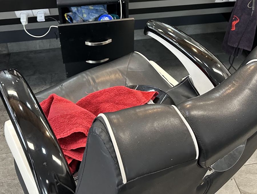 Schwarzer Barber-Stuhl mit rotem Handtuch